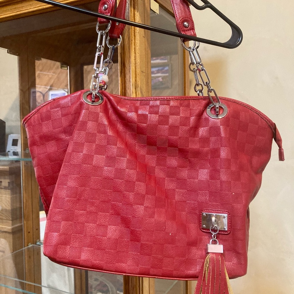 Red vegan leather shoulder bag with chain and tassels.